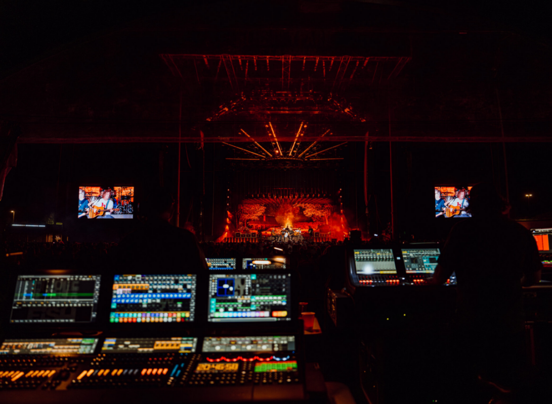 Front of house sound board with stage in background.