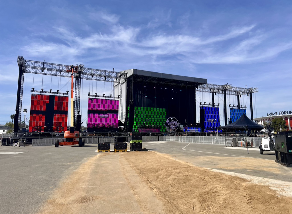 Large stage outdoors with barrier and gear in front in a parking lot